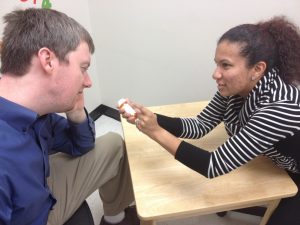 woman shows a medical prescription bottle to a man