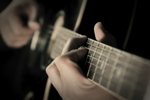 Photo of a person's hand picking a guitar.