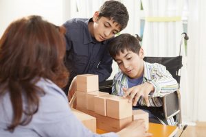 Photo of a boy helping his brother stack wooden blocks