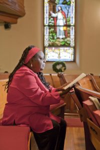 A photo of a woman reading the Bible inside of a church.