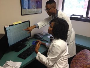 Ryan Lang showing something on a computer screen to a resident 