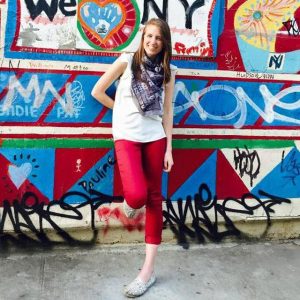 Summer research intern Kelsey Hopland, standing in front of a mural.