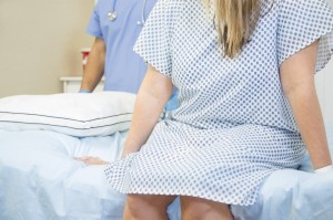 A woman sitting in a hospital gown on a bed