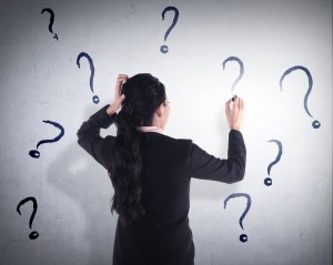 A businesswoman writes question marks on a wall