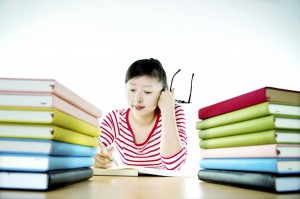 Surrounded by textbooks, a student works on a paper