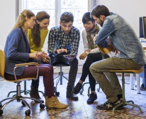 group of young people gathered around a tablet