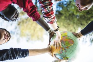 student gathered together touching a globe