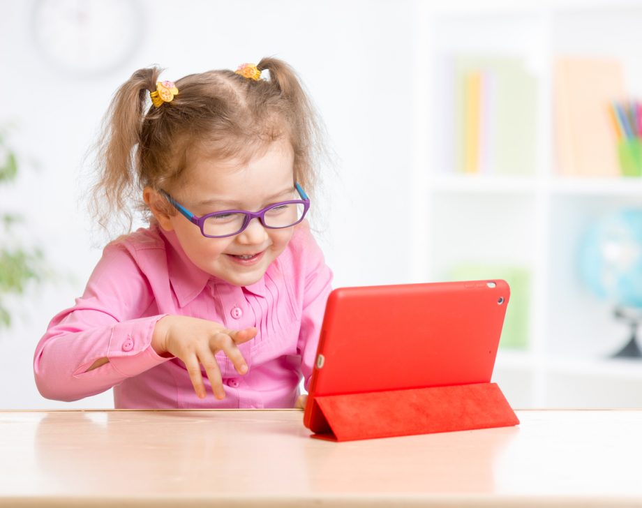 Kid with tablet PC in glasses learning with great interestc