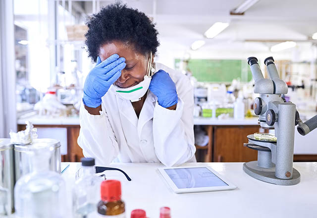 Shot of a female scientist looking stressed out while working in a lab