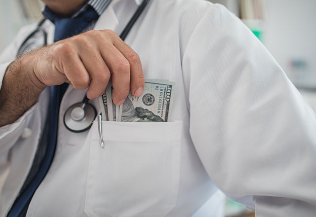 Doctor putting money in his pocket in his office, cropped photo.
