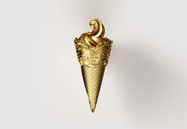 A gold-leaf ice cream cone with sprinkles on a white backdrop..