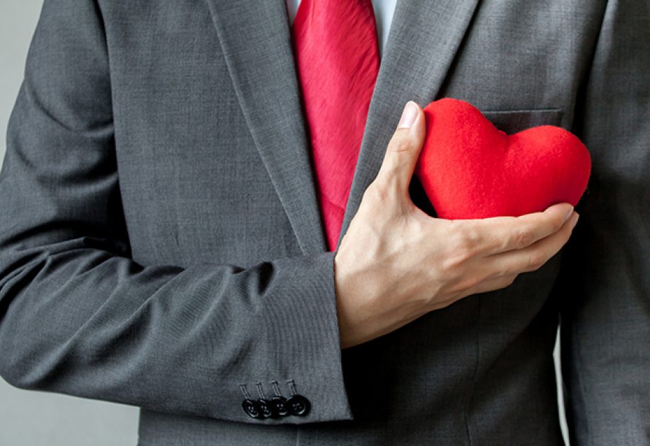 Businessman holding a red felt heart to his chest.