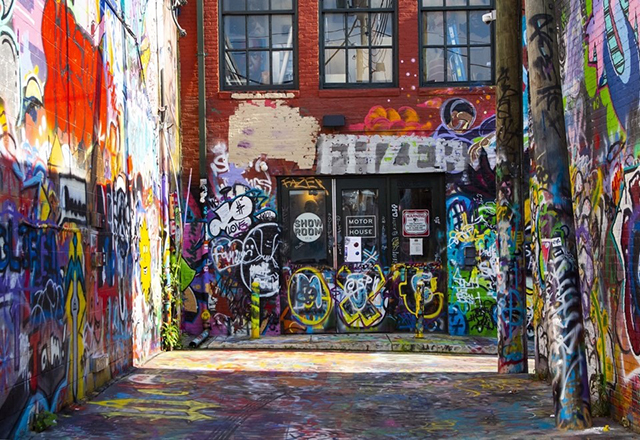An alleway covered in layers of colorful graffiti.