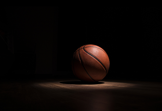 A basketball sits alone in a spotlight.