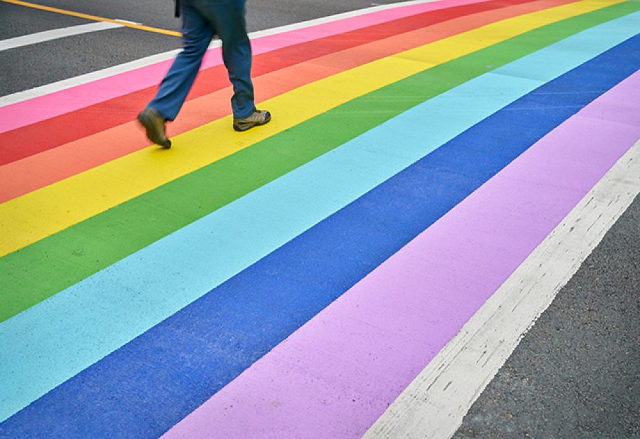 A pedestrian using the rainbow colored crosswalk in downtown Vancouver.