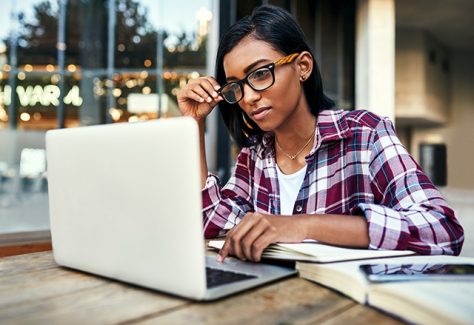 Cropped shot of a young female student using a laptop outside on campus.