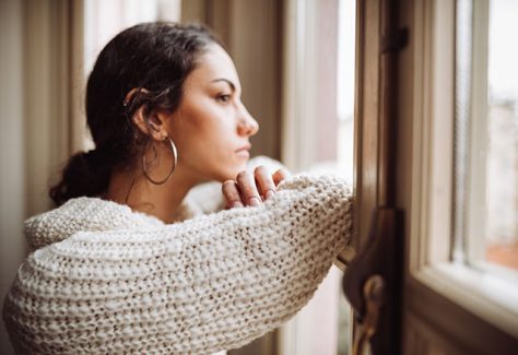 A pensive woman looks out of a window.
