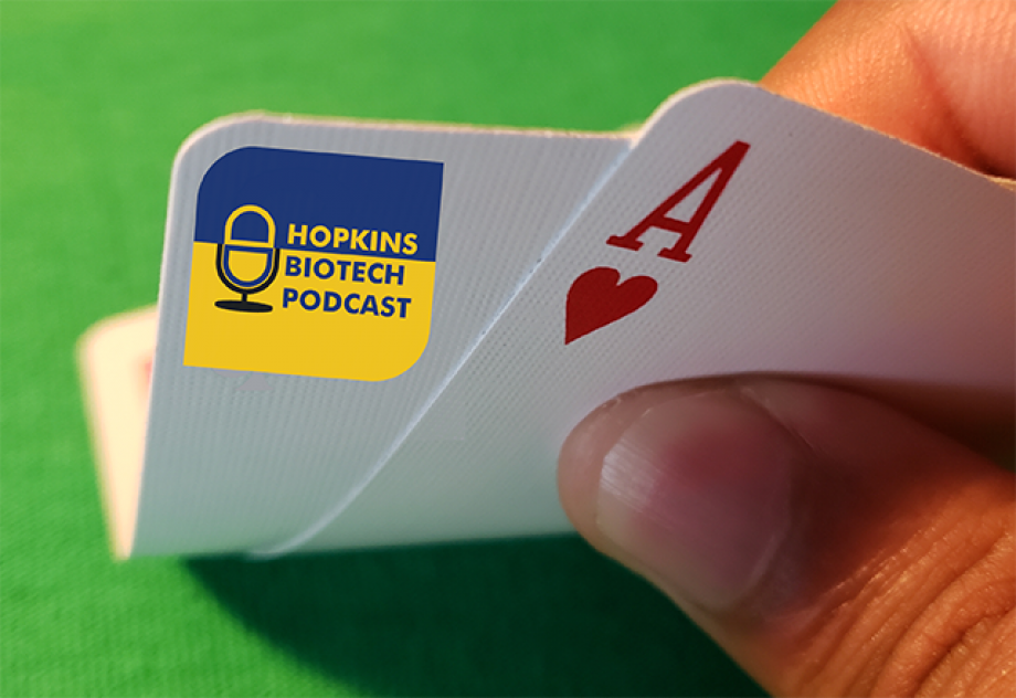 A close up of a pair of playing cards, one of which has the Hopkins Biotech Podcast logo.