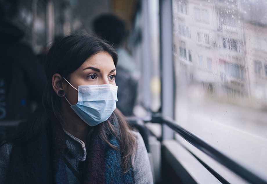 Young woman wearing protective face mask, sitting in bus transportation in the city.