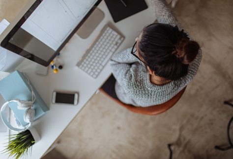 Photo of a young woman working on her computer, from her home office.