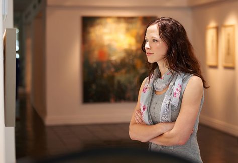 Shot of a young woman looking at paintings in a gallery