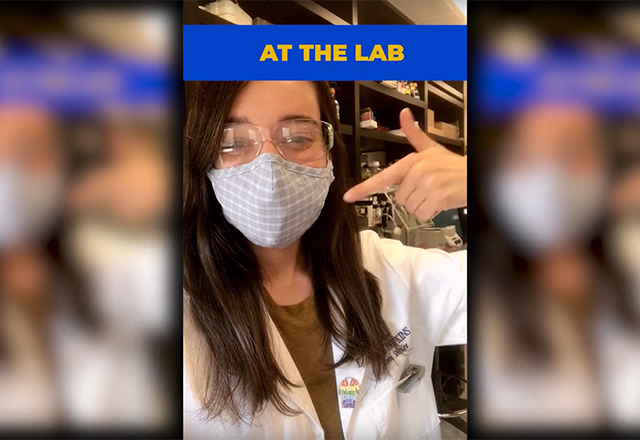 A Hopkins student points to her mask while in the lab.