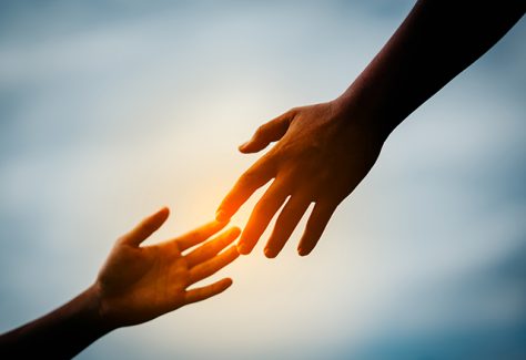 Two hands reach to connect with one another.