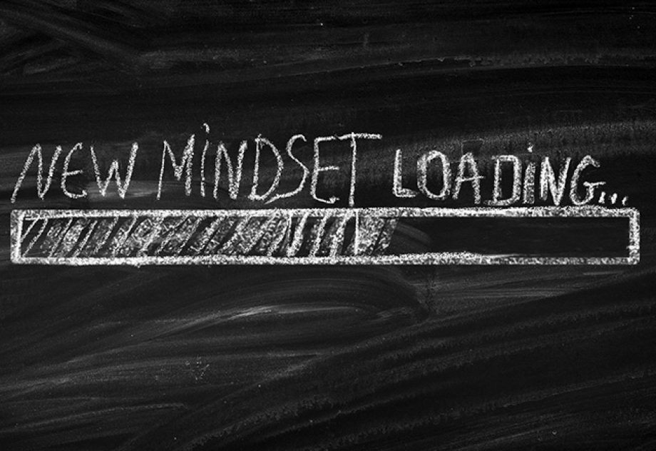 A chalkboard with "New Mindset Loading" written in white chalk.