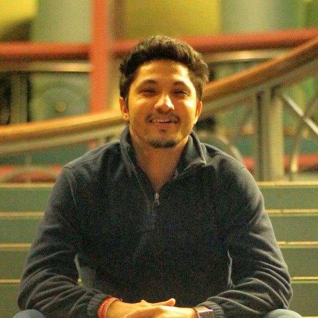 Surya sits, smiling.