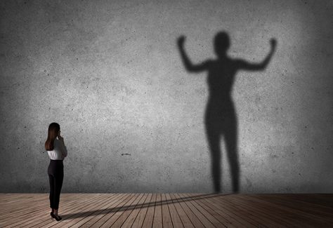 A woman stands, casting a powerful, larger-than-life shadow.