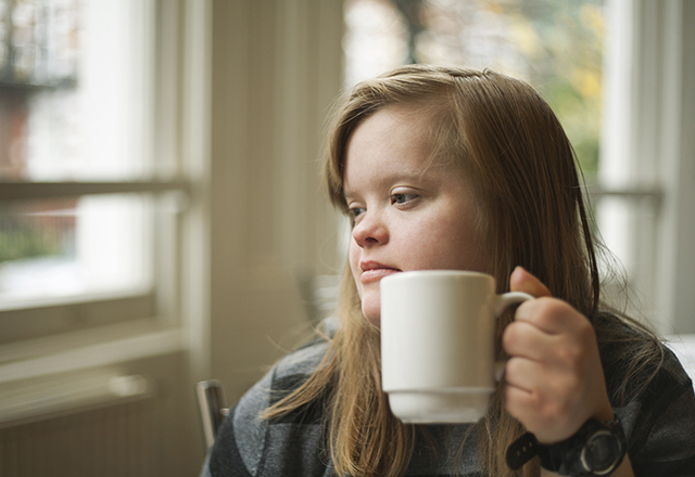 Portrait of girl with down syndrome having breakfast.