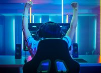 玩家坐在电脑前，高举双臂表示胜利。