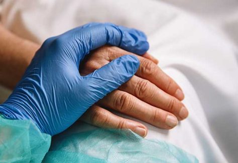 Gloved Doctor's hand holding patient's hand.