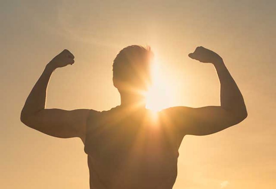 Person flexing silhouetted by the sun in the background
