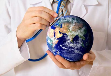 Doctor hold a stethoscope to a small globe.