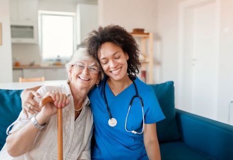 Portrait of Smiling Senior Woman and Her Mixed Race Female Caregiver Together at Nursing Home. Caring Female Doctor Taking Care of a Happy, Elderly Woman
