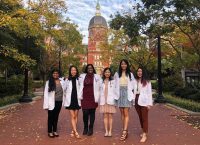 Friends in white coats stand on Johns Hopkins campus