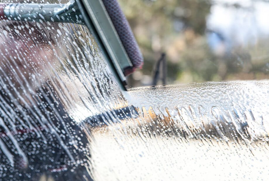 Action shot of a car windshield being cleaned with a squeegee.