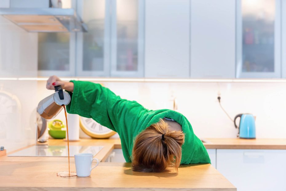 Fatigued woman with head down on table pours a cup of coffee