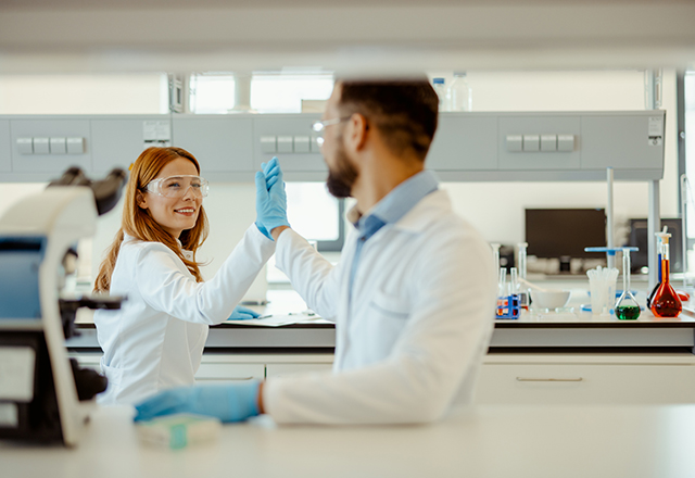 Shot of two scientists giving each other a high five while conducting research in a laboratory